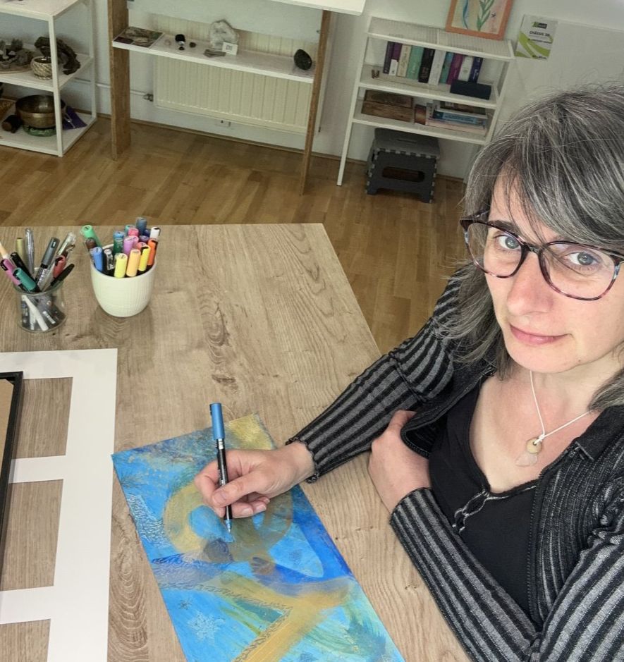 Valérie Pereira peignant une œuvre en bleu et or à son atelier